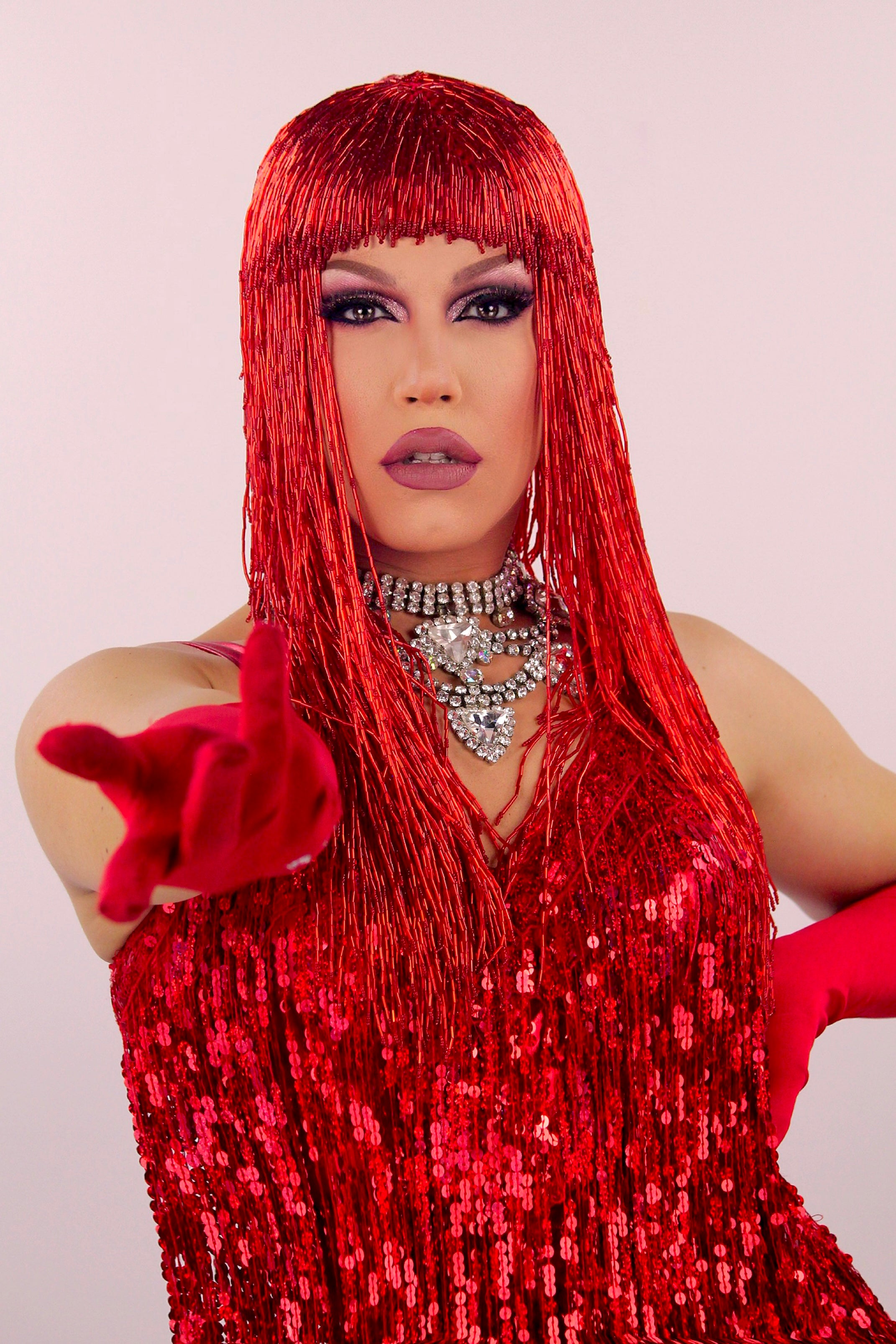 Une artiste drag queen de l'agence NA Events avec des cheveux rouges à franges et une tenue rouge à paillettes, posant pour une prestation lors de mariages ou événements privés.