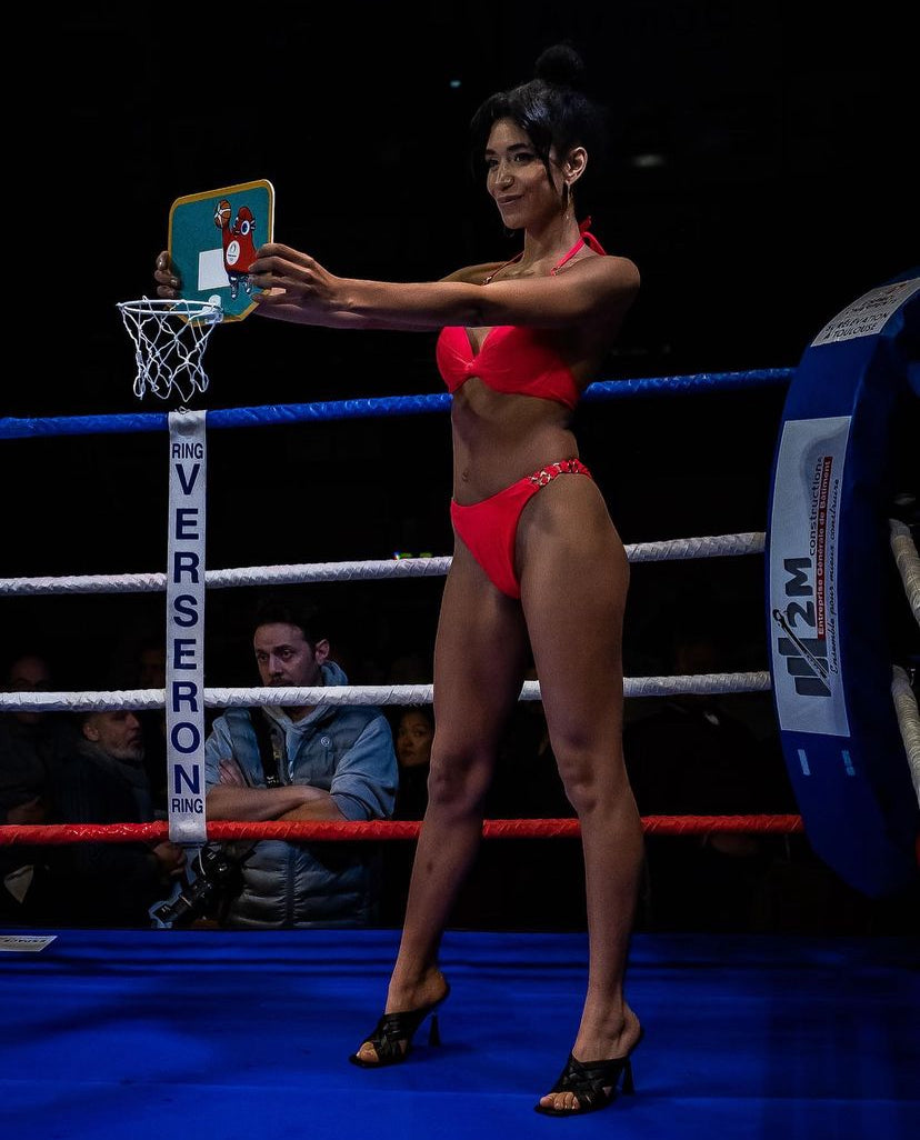 Une ring girl de l'agence NA Events présente sur un ring de boxe lors d'un gala.