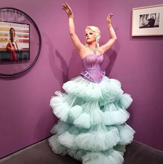 Artiste Drag Queen de l'agence NA Events en pleine performance avec une perruque blonde volumineuse et une tenue rose étincelante.
