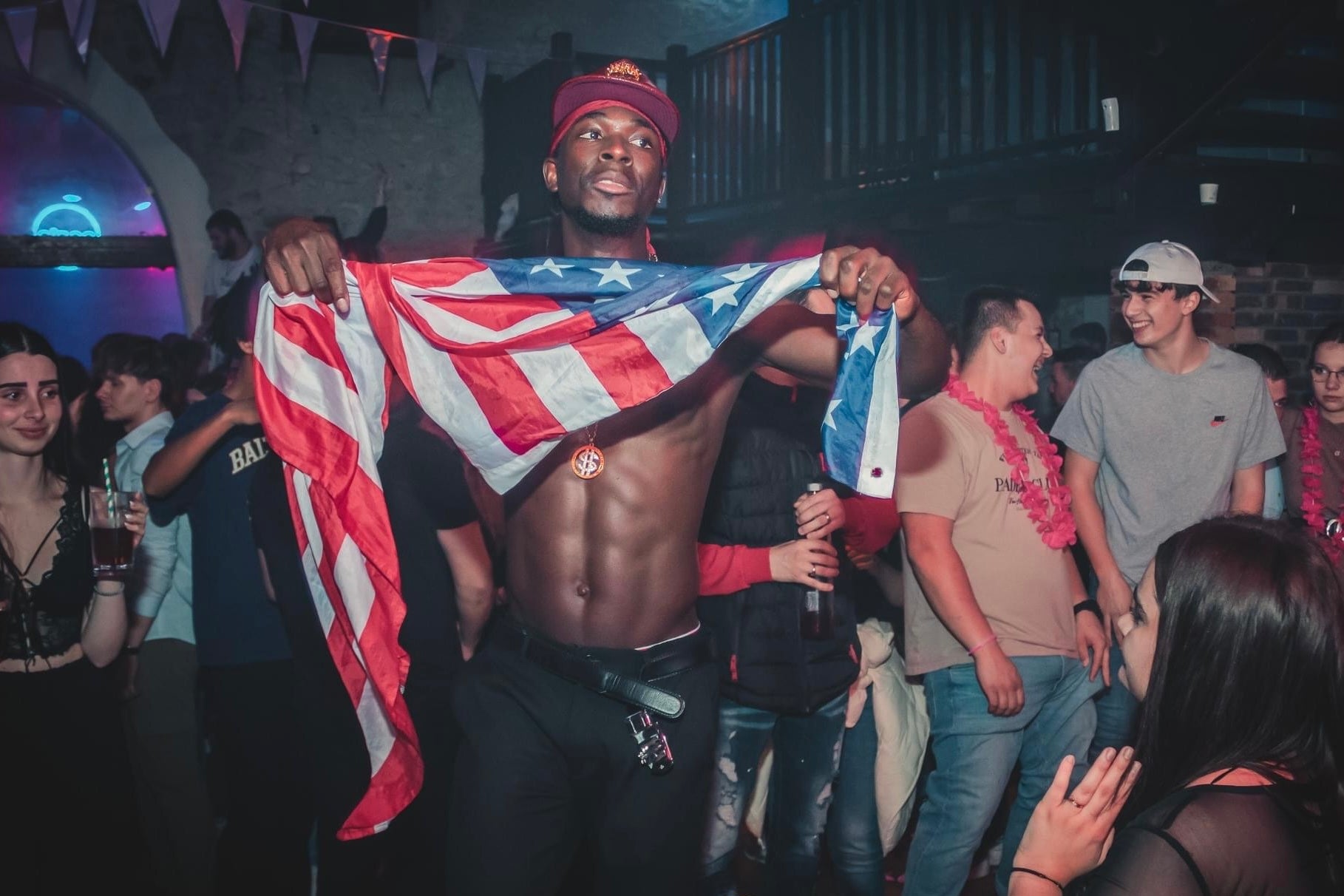 Un artiste stripteaseur de l'agence NA Events dansant avec un drapeau américain lors d'une prestation de striptease en club. 